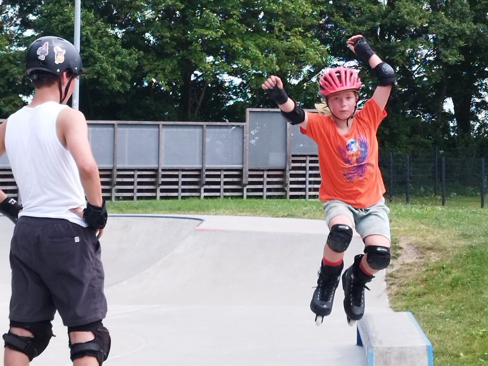 Kind auf Inlineskates grindet auf der Betonkante im Skatepark Burg auf Fehmarn