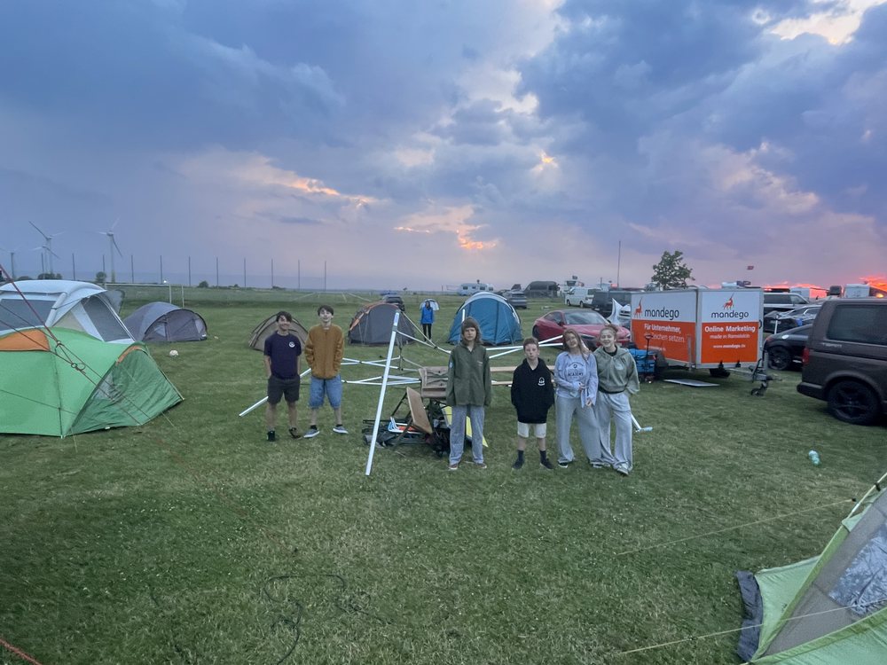 Die Crew steht abends unter dramatischem Himmel zusammen